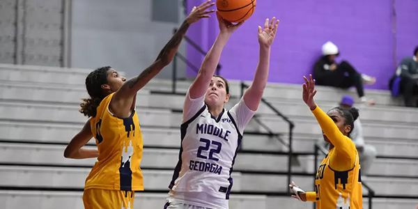 mag womens basketball player shooting over two defenders